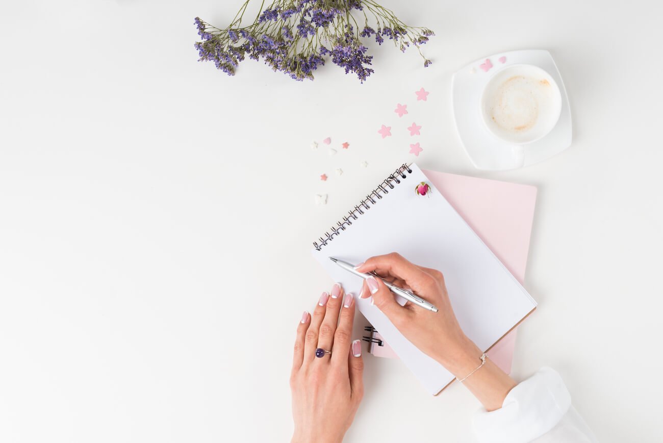 Shadow work prompts. Image shows a woman writing in a diary.