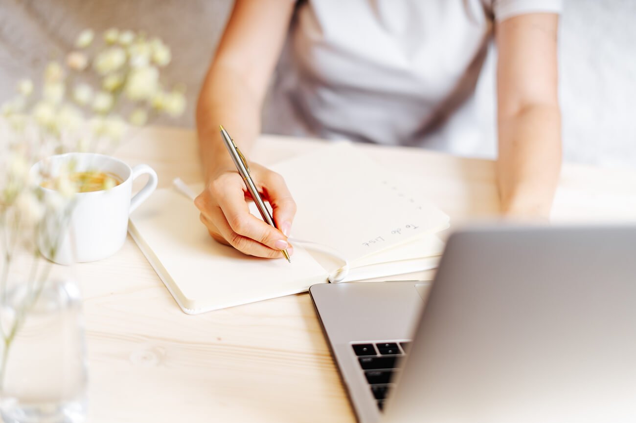 Shadow working | shadow work | Image shows a woman sitting at a desk writing.