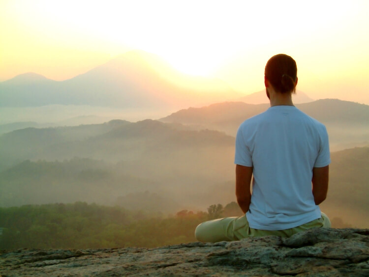 Image shows a man watching the sunrise.