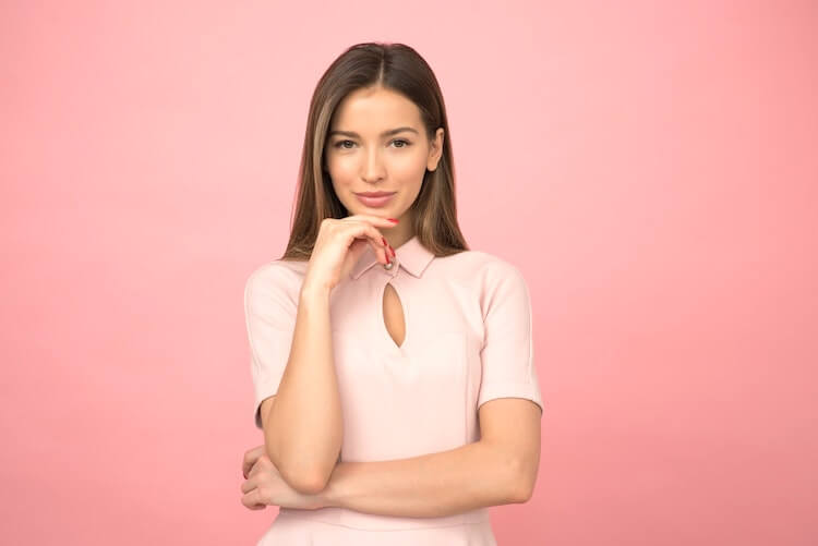 Casual corporate headshot of a woman against a salmon pink background.