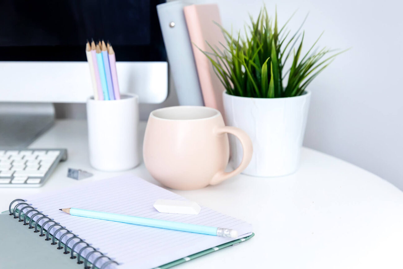 Night journal prompts | Grey journal on a white desk, surrounded by pastel coloured items.