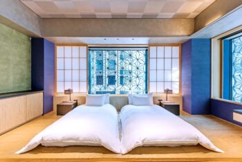 Single beds with white bedding in a bedroom with blue walls.